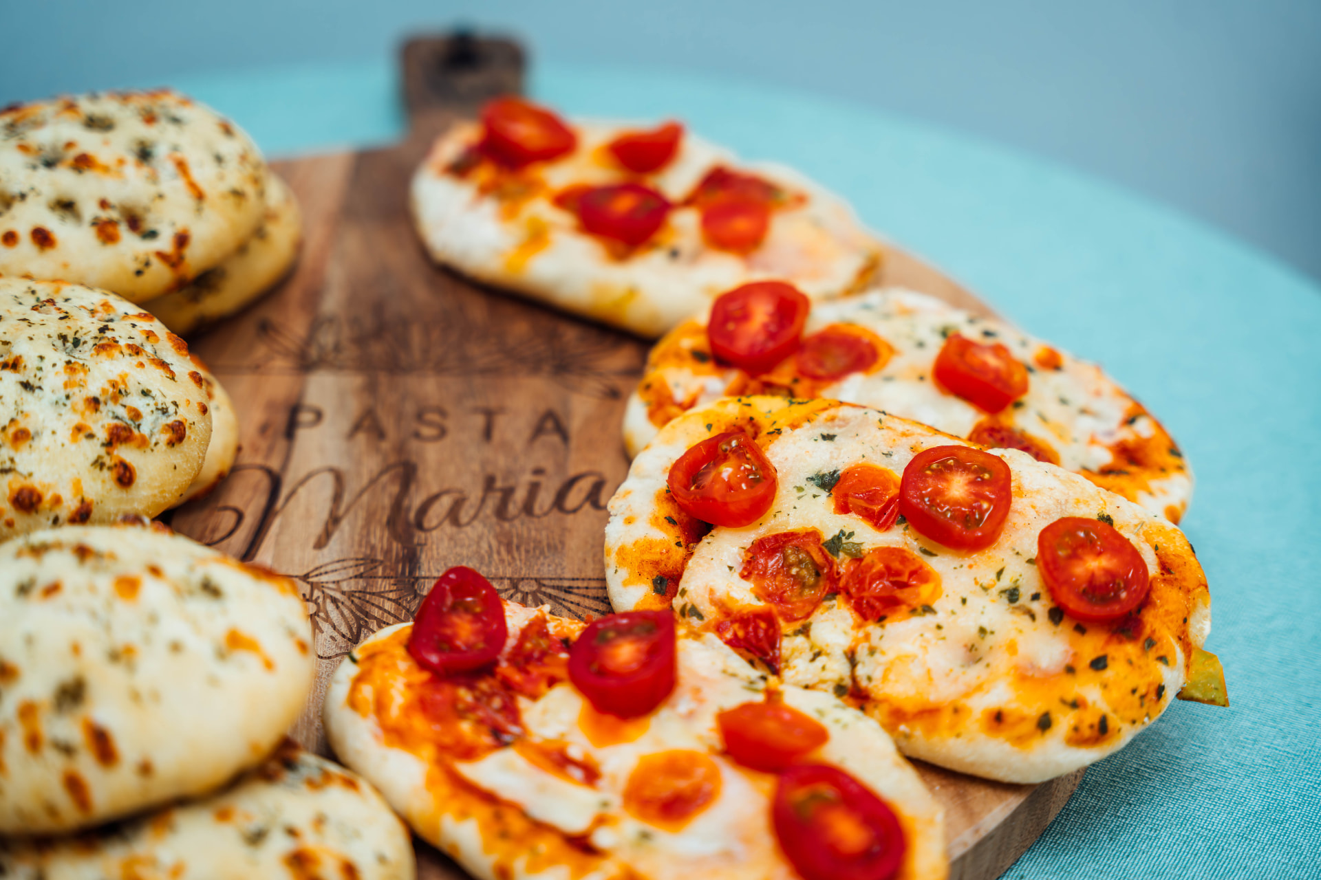 Focaccia's en mini-pizza's van Pasta Maria op een houten plank